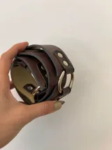 Cinto de cuero marrón con hebilla metálica plateada y doble pasador.