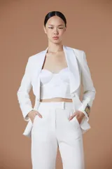 Saco tipo blazer de Natalia Antolín, color blanco, con solapas de satén en contraste, cierre frontal con un botón y detalle de parche con logo en la manga.