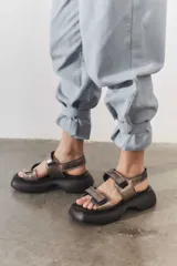 Sandalias de plataforma con suela de goma negra y tiras de cuero sintético color beige con cierre de velcro ajustable.