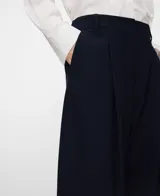 Pantalón de tiro alto, corte barrel y diseño ancho, color azul marino, con trabillas en la cintura, pliegues frontales y bolsillos laterales.