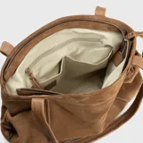 Bolso tipo tote bag color marrón camel, confeccionado en descarne vacuno gamuzado y cuero graneado. Tiene doble asa corta de hombro y correa larga extraíble. Presenta detalles fruncidos en los laterales, tres compartimentos interiores y dos bolsillos exteriores.