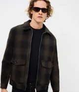 Campera de franela con estampado de cuadros, cuello tipo polo, cierre frontal con cremallera y bolsillos delanteros con solapa y botón. Cuenta con forro interior para mayor calidez.