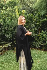 Ruana de lana negra con flecos en los bordes y diseño con caída en picos en la espalda.