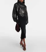 Campera bomber corta de cuero sintético negro, con cuello alto, cierre frontal y detalles de botones metálicos plateados en hombros y bolsillos frontales.