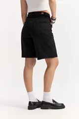 Bermuda larga de jean negro, de corte recto y tiro alto, con largo por encima de la rodilla. Cuenta con un lazo ajustable en la cintura y detalles desflecados en el ruedo.