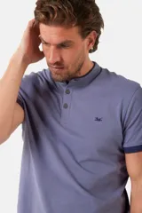 Remera blanca de manga corta con cuello mao y cierre frontal parcial con botones. Presenta detalles en color gris azulado en el cuello y en los bordes de las mangas.