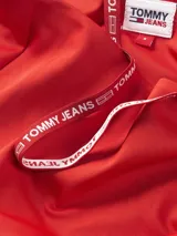 Vestido corto ajustado Tommy Jeans color rojo, con diseño asimétrico de un solo hombro y una manga larga. Presenta un tirante con el logo de la marca y un corte ajustado al cuerpo.