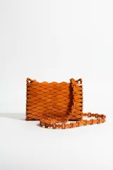 Bandolera artesanal color naranja, confeccionada con cuentas y piezas de madera formando un patrón geométrico romboidal, con correa larga estructurada del mismo material.