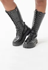 Botas negras de caña alta con cordones y cierre lateral, suela track y plataforma.