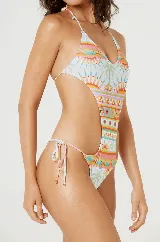 Malla enteriza blanca con estampado de palmeras, soles y figuras geométricas en tonos pastel. Diseño con escote halter y aberturas laterales.