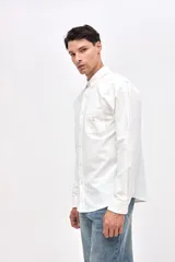 Camisa de corte regular fit confeccionada en algodón, con cuello clásico, cierre frontal de botones y bolsillo en el pecho con detalle bordado.
