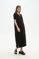 Vestido midi de corte holgado, color negro, con mangas cortas, cuello en V y detalle de cuentas decorativas en el escote.