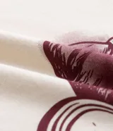 Remera de algodón color crema con cuello redondo y mangas cortas. Presenta un estampado frontal con temática parisina que incluye la palabra 'Paris', un dibujo de una taza de café sobre un croissant y la frase 'Croissant & Crème'.