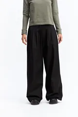Pantalón de vestir negro de corte wide leg, con cintura elástica ajustable mediante cordón, pliegues frontales y diseño holgado.