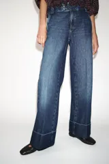Jeans de tiro bajo con pernera recta y bajo con vuelta. Cuenta con cinco bolsillos y cierre frontal con cremallera y botones.