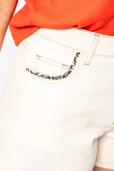 Short de jean color natural, tiro alto y detalle de estampado animal print en el bolsillo delantero.