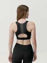 Top deportivo negro de alta sujeción con tecnología performance y motivo estampado reflectante en la espalda.