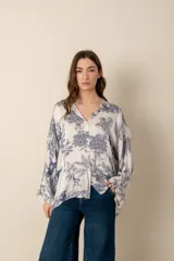 Camisa blanca con estampado floral y de animales en azul, de corte amplio y mangas largas.