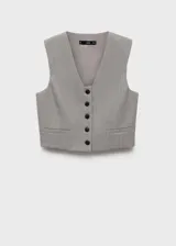 Chaleco de estilo sastre con diseño crop, cuello de pico y cierre frontal de botones. Presenta dos bolsillos de ribete en la parte delantera y cuenta con forro interior.