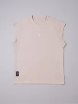 Musculosa de mujer color beige claro, corte oversize, con mangas cortas tipo ranglán y cuello redondo. Presenta un pequeño bordado en el centro del pecho.