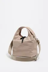 Bolso bandolera de estructura blanda marca Bimba y Lola, confeccionado en nylon con detalles en cuero. Presenta doble asa de mano, correa de tejido regulable y extraíble, cierre de cordón y logo metálico en el frente.