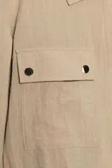 Chaqueta corta marrón de cuello solapa y manga remangada por debajo del codo. Presenta bolsillos delanteros de plastrón con solapa, bajo ajustable con cordón interior y cierre frontal con botones.