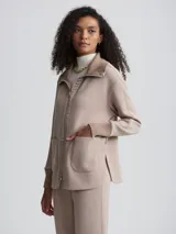 Campera color beige de corte holgado, con cierre frontal, cuello alto y bolsillos de parche grandes.