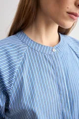 Camisa de manga corta a rayas azules y blancas, con cuello mao y cierre frontal oculto.