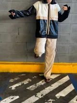 Campera con cuerpo de corderito color beige, mangas y parte inferior de cuero sintético negro con textura tipo cocodrilo. Tiene cuello estilo camisa con solapas de corderito negro, cierre frontal con cremallera y bolsillos laterales.