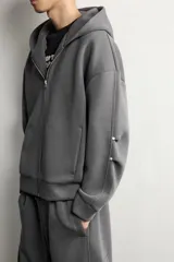 Sudadera con capucha y cierre frontal de cremallera, confeccionada en tejido doble compacto de mezcla de algodón. Presenta un corte relajado, mangas largas con puños acanalados, bolsillos laterales de vivo y bajo con acabado en rib.