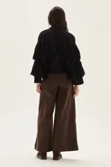 Cardigan de tejido de punto con detalles calados, trenzas y flecos en mangas y espalda. Presenta cierre frontal con botones, cuello redondo y mangas tres cuartos.