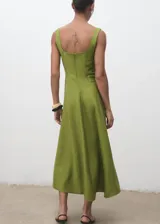 Vestido midi de corte evasé en color verde oliva, con escote cuadrado, tirantes anchos y costuras decorativas verticales que estilizan la silueta. Cuenta con cierre de cremallera en la parte posterior y forro interior.