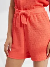 Short de tiro alto con textura arrugada, cuenta con cintura elástica y un lazo decorativo para anudar al frente.