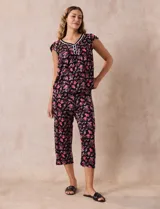 Conjunto de pijama marca René Rofé, compuesto por una remera de escote en V con botones y un pantalón capri con cintura elastizada, ambos en tejido soft estampado con motivos florales en tonos celeste y blanco.