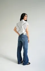 Vestido camisero corto blanco de algodón con bordados negros, cuello camisero, cierre frontal con botones y sin mangas.