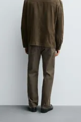 Pantalón de corte regular fit confeccionado en tejido ligero de algodón color marrón. Presenta diseño clásico de cinco bolsillos, cierre frontal con cremallera y botón metálico.