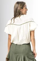 Blusa de algodón off white con cuello mao, botones frontales y mangas globo. Cuenta con canesú destacado con bordado floral en color azul marino.