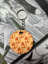 Llavero redondo con diseño estampado de Charmander sobre fondo naranja.
