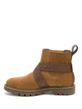 Bota corta de gamuza color marrón, con diseño de caña media y elástico lateral. Presenta una tira de cuero cruzada con hebilla metálica y tachuelas decorativas. Cuenta con suela de goma dentada y logo de la marca grabado en el lateral.