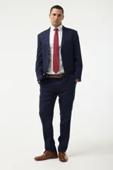 Traje completo de dos piezas en color azul marino, compuesto por saco de corte clásico con solapas de muesca y pantalón de vestir a juego. Incluye camisa blanca, corbata roja y cinturón de cuero marrón.