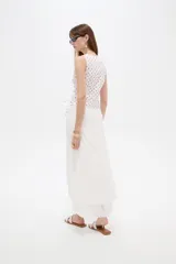 Musculosa de algodón sin mangas, de corte cruzado con cuello en V y diseño holgado, color blanco con estampado de lunares bordó y lazo lateral para ajustar.