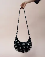 Bolso de mano tipo hobo, confeccionado en gamuza color marrón oscuro, decorado con tachas metálicas circulares en toda su superficie. Cuenta con un asa corta integrada y un diseño curvo distintivo.