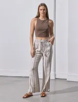 Pantalón largo de lino color beige con rayas verticales marrones. Tiene pretina ancha en punto smock con lazo ajustable, bolsillos verticales delanteros y bolsillos aplicados traseros.