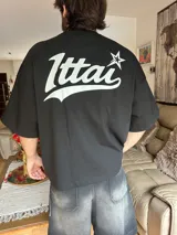 Remera rosa de corte holgado con estampado trasero de la palabra "Ittai" en blanco con una estrella.