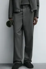 Pantalón regular fit color marrón oscuro, confeccionado en tejido con viscosa. Cuenta con cintura elástica, bolsillos delanteros y detalle de bolsillos traseros de vivo. El cierre frontal es con cremallera y botón.