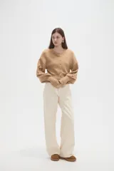 Saco de punto color beige, con cuello redondo, cierre frontal con botones y mangas largas con puños acanalados.