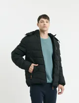 Campera capitoneada de poliéster color negro, con capucha desmontable, cierre frontal y bolsillo en el pecho con cierres engomados y tiradores en color naranja.