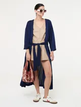 Saco largo azul marino con fajín, de jersey de lúrex con aberturas laterales, mangas largas y bolsillos laterales en costura.