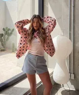 Chaqueta liviana de color rosado con estampado de lunares negros, cuello alto, cierre frontal con broches y cordón ajustable en la cintura. Presenta un calce relajado y puños regulables.