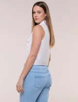 Camisa sin mangas de rayón texturado color blanco, de corte crop con cierre frontal de botones y lazos para anudar en el frente. Cuenta con cuello camisero, detalles de brillos en los hombros y bolsillos plaqué con solapa en el pecho.